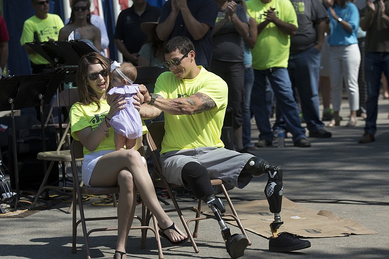 Jason Smith, right, and his wife Lauren, left, hold their daughter Lyla Jean during a dedication ceremony Saturday, May 9, 2015, at the Smith family's new home in Ringgold, Ga. The Steps 2 Hope organization worked with hundreds of volunteers and tens of thousands of dollars in donations to construct a new home for Smith, a veteran who lost his legs in Afganistan, and his family in just under two weeks time.