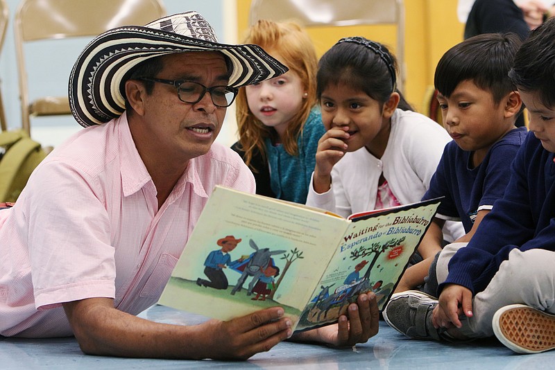 Luis Soriano lies down on the floor as he reads to Magdalen Bruce, 6, Jacqueline Garcia, 7, Luis Garcia, 6, and Miguel Gonzalez, 6, Monday, Oct. 23, 2017, at East Lake Elementary School in Chattanooga, Tenn. Soriano visited East Lake Monday where he read a book that was written about him and gave a presentation about his "Biblioburro" mobile library project.