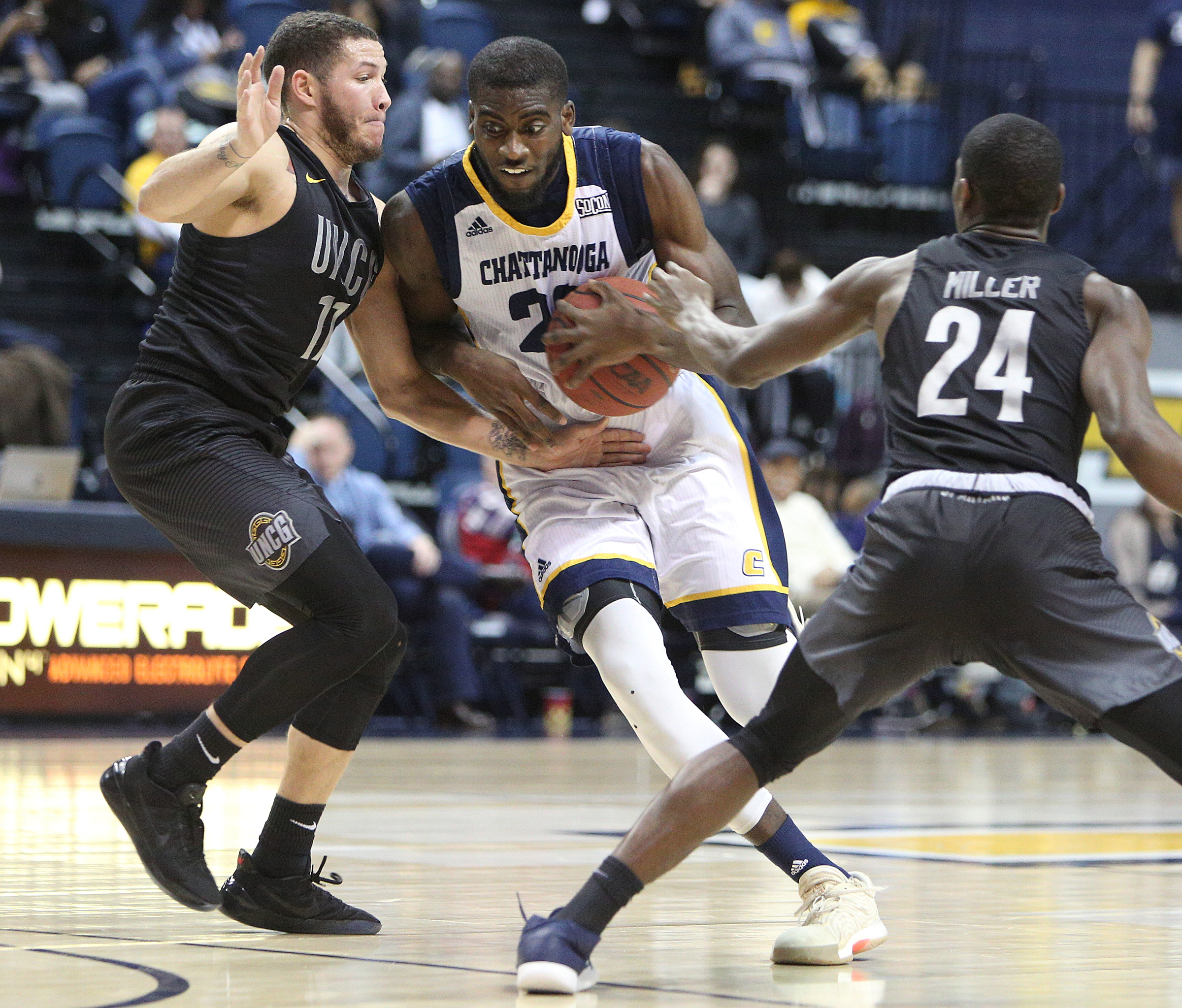 University of Tennessee at Chattanooga's Makinde London (22) pushes his way through University of North Carolina Greensboro's Demetrius Troy (11) and Isaiah Miller (24) during the UTC vs. University of North Carolina Greensboro men's basketball game Monday, Jan. 29, 2018 at McKenzie Arena at UTC in Chattanooga, Tenn.