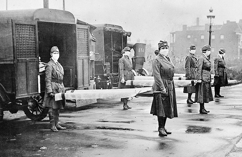 In this October 1918 photo, St. Louis Red Cross Motor Corps personnel wear masks as they hold stretchers next to ambulances in preparation for victims of the influenza epidemic. A century after one of history's most catastrophic disease outbreaks, scientists are rethinking how to guard against another super-flu such as the 1918 influenza that slaughtered tens of millions as it swept the globe in mere months. (Library of Congress photo via The Associated Press)