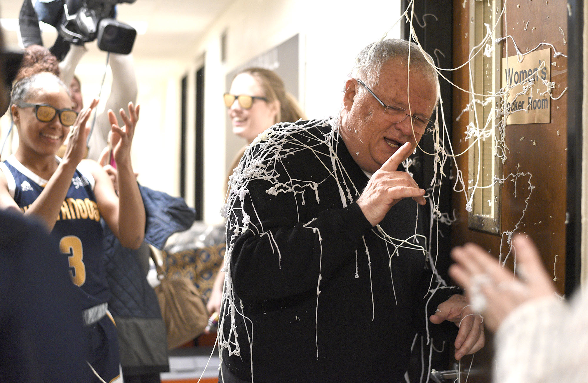 Covered in silly string by his players Chattanooga head coach turns to address his players outside the locker room after his 900th victory. The University of Tennessee Mocs visited the Western Carolina Catamounts in Southern Conference women's basketball action at the Ramsey Center in Cullowhee, North Carolina on February 1, 2018