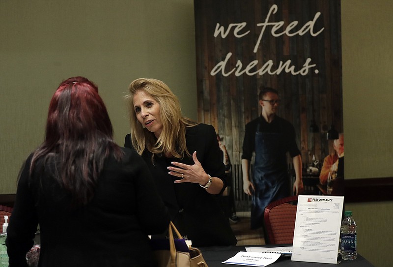 In this Tuesday, Jan. 30, 2018, photo, Grace Ochoa, of Performance Food Service, right, talks with a job applicant at a JobNewsUSA job fair in Miami Lakes, Fla. 