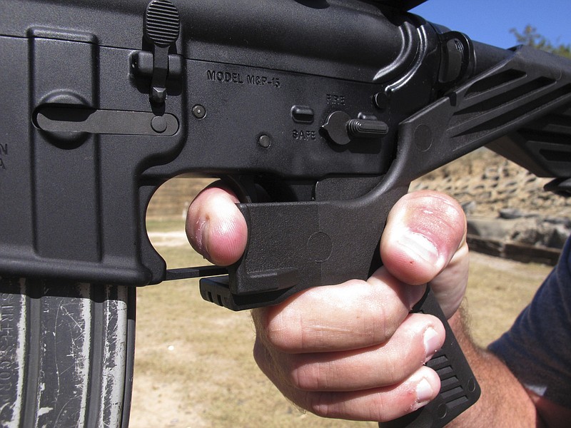 In this Oct. 4, 2017, file photo, shooting instructor Frankie McRae demonstrates the grip on an AR-15 rifle fitted with a bump stock at his 37 PSR Gun Club in Bunnlevel, N.C. Some states and cities are taking the lead on banning bump stocks as efforts stall in Washington. The controversial device was used in the Las Vegas shooting, allowing a semi-automatic rifle to mimic a fully automatic firearm. Gun-control advocates say the push fits a pattern in gun politics: inaction in Washington that forces states to take charge. (AP Photo/Allen G. Breed, File)