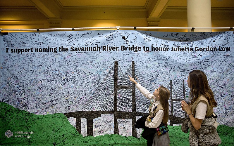 Girl Scouts Veronica Ward, 11, right, and Audra Duncan, 12, look at a signed banner on display at the Georgia Capitol during a rally to convince legislators to strip the name of segregationist former Gov. Eugene Talmadge from a Savannah bridge in Atlanta, Tuesday, Feb. 6, 2018. They hope the bridge will be renamed in honor of Girl Scout's founder Juliette Gordon Low. (AP Photo/David Goldman)