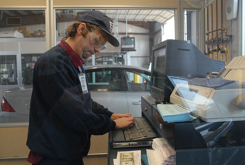 An employee types in information to complete an emissions test at the Emissions Testing Center on Riverfront Parkway.