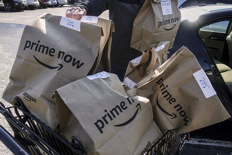 Amazon Prime Now bags full of groceries are loaded for delivery by a part-time worker outside a Whole Foods store, Thursday, Feb. 8, 2018, in Cincinnati. Amazon, which owns Whole Foods, plans to roll out two-hour delivery at the organic grocer this year to those who pay for Amazon's $99-a-year Prime membership. Amazon.com Inc. said deliveries started Thursday in Austin, Texas; Cincinnati; Dallas; and Virginia Beach, Va. (AP Photo/John Minchillo)