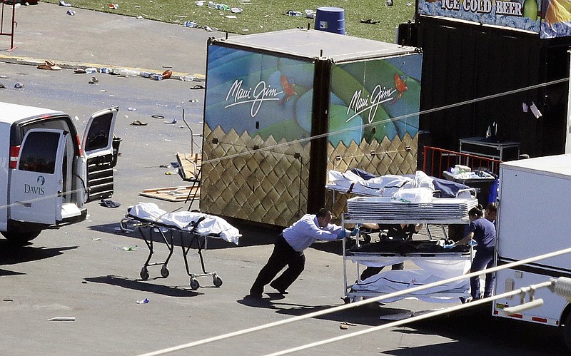 FILE - In this Oct. 2, 2017, file photo, investigators load bodies from the scene of a mass shooting at a music festival near the Mandalay Bay resort and casino on the Las Vegas Strip in Las Vegas. 