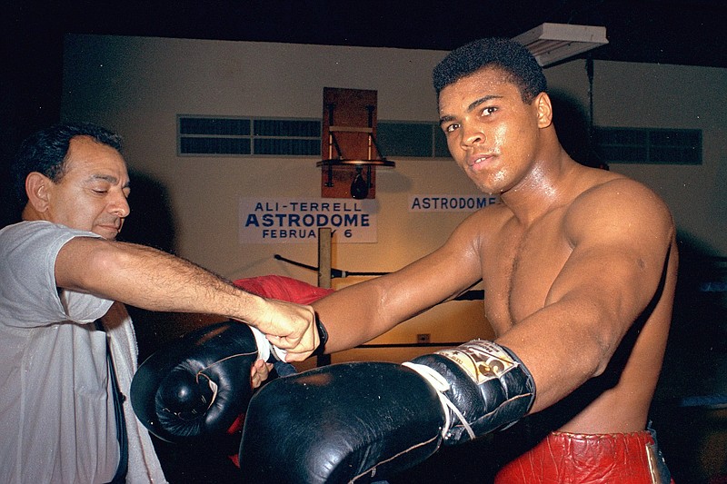 In this February 1967, file photo, Muhammad Ali gets his gloves laced by trainer Angelo Dundee while training in Houston, Texas, for a title fight against Ernie Terrell. Ali never spent a day in prison for his actions even though he was sentenced to serve five years for draft evasion before the Supreme Court overturned his case on a technicality. But many black athletes have paid when taking a stand, or a knee, for speaking out for social or political change. Ali lost the heavyweight title and spent three years in forced exile from the ring. (AP Photo)/File)