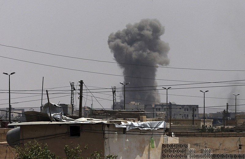 In this July 17, 2017 file photo, smoke rises from a coalition airstrike which attacked an Islamic State militant position, on the front line on the western side of Raqqa, northeast Syria. The U.S. says an American detained by U.S. forces was carrying thumb drives containing bomb-making files and documents describing work he did for the Islamic State group at the time he surrendered in Syria last year. The government's justification for holding the detainee without charge is part of documents filed late Wednesday, Feb. 14, 2018, in federal court. (AP Photo/Hussein Malla, File)