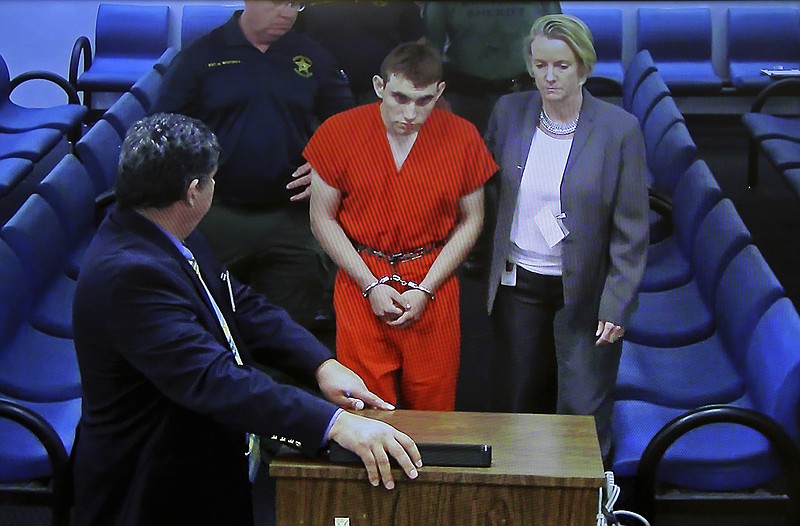 A video monitor shows school shooting suspect Nikolas Cruz, left, with public defender Melisa McNeille, making an appearance before Judge Kim Theresa Mollica in Broward County Court, Thursday, Feb. 15, 2018, in Fort Lauderdale, Fla. Cruz is accused of opening fire Wednesday at the school killing more than a dozen people and injuring several. (Susan Stocker/South Florida Sun-Sentinel via AP, Pool)