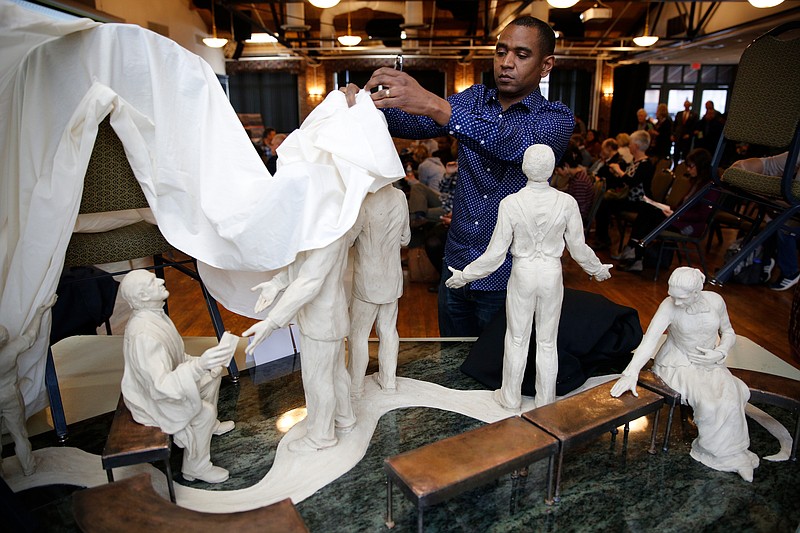 Designer Rodney Leon uncovers his collaborative concept with sculptor Ai Qiu Hopen for an Ed Johnson memorial during a presentation of artist designs at Bessie Smith Cultural Center on Thursday, Feb. 15, 2018, in Chattanooga, Tenn. Three semi-finalist teams presented their designs for the memorial to Johnson, who was lynched from the Walnut Street Bridge by a mob in 1906.