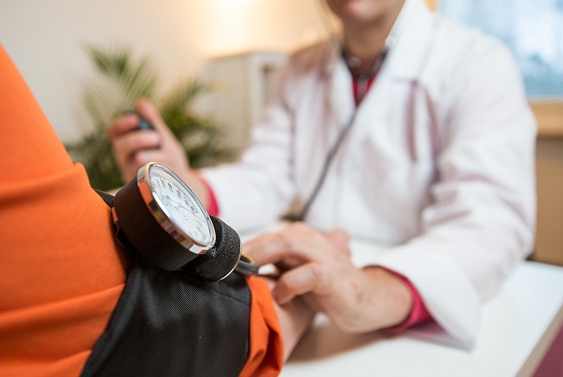 Male doctor holding hand of patient in hospital. Sick senior woman having a doctor appointment. Trust and support concept.