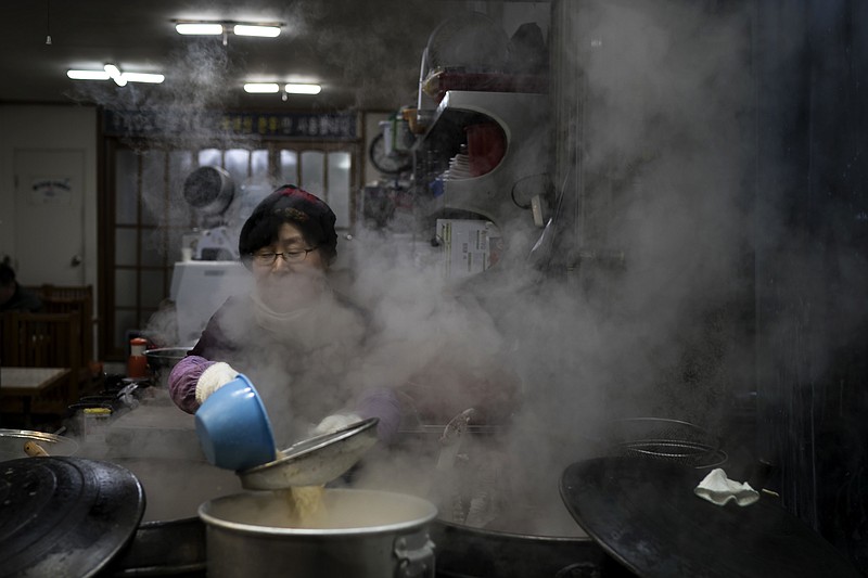 A woman cooks at a restaurant in Gangneung, South Korea, Monday, Feb. 12, 2018.  Korean food is some of the world’s finest - savory, salty soups with fish so tender it falls off the bone; thick slabs of grilled pork and beef backed with spicy kimchi that many Korean grandmothers swear cures the common cold. But it’s very different from what many foreign Olympians are used to. (AP Photo/Felipe Dana)