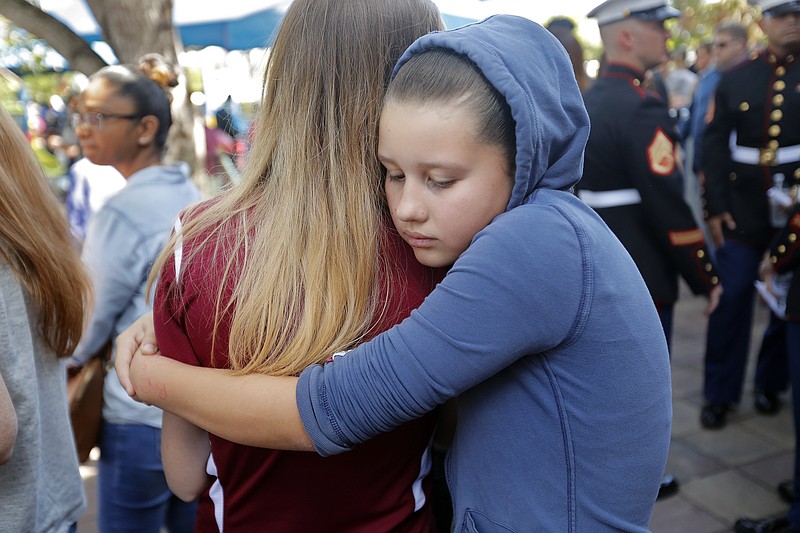 Kaitlynn Cooper, 12, facing, hugs her friend Allison Shonk, 18, a student at Marjory Stoneman Douglas High School, during a vigil at the Parkland Baptist Church, in Parkland, Fla., Thursday, Feb. 15, 2018. Nikolas Cruz, a former student, was charged with 17 counts of premeditated murder Thursday morning. (AP Photo/Gerald Herbert)