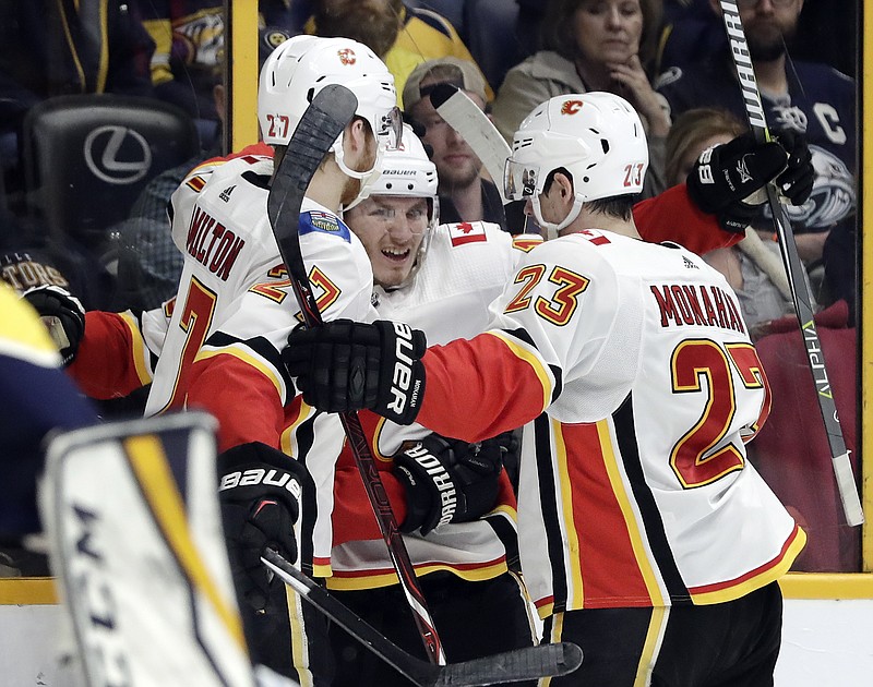 Calgary Flames left wing Matthew Tkachuk, center, celebrates with Dougie Hamilton (27) and Sean Monahan (23) after scoring a goal against the Nashville Predators in the first period of an NHL hockey game Thursday, Feb. 15, 2018, in Nashville, Tenn. (AP Photo/Mark Humphrey)