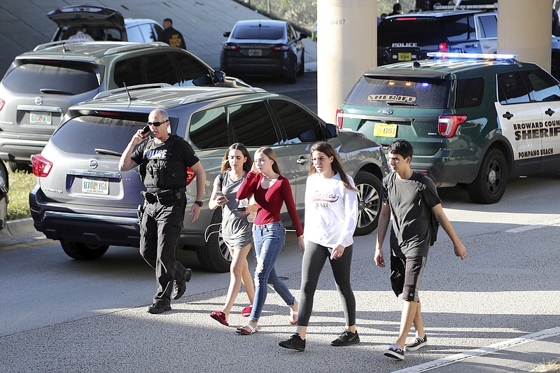 In this Wednesday, Feb. 14, 2018 file photo, teens, who walked out from the direction of the high school, are escorted by police following a shooting at Marjory Stoneman Douglas High School, in Parkland, Fla. It was the final period of the day at the school and Jonathan Blank was in history class, learning about the Holocaust. Across campus five of his friends, pals since grade school, sat in different classrooms watching the clock, when a former student opened fire at the school, killing more than a dozen people and injuring others Wednesday afternoon. (Amy Beth Bennett/South Florida Sun-Sentinel via AP, File)