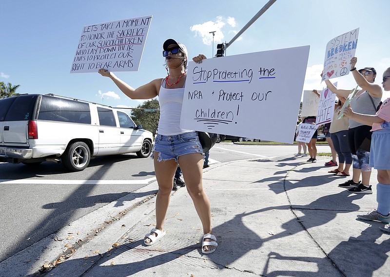 Juliana Cruz stands on a street corner holding up an anti gun sign in Parkland, Fla., on Saturday, Feb. 17, 2018.