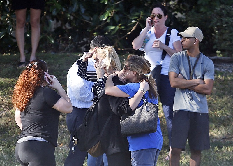 Anxious family members wait for news of students as two people embrace Wednesday in Parkland, Fla. A shooting at Marjory Stoneman Douglas High School killed 17 and sent students rushing into the streets as SWAT team members swarmed in and locked down the building. (AP Photo/Wilfredo Lee)