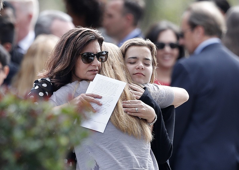 Mourners hug as they leave the funeral of Alaina Petty, in Coral Springs, Fla., Monday, Feb. 19, 2018. Petty was a victim of Wednesday's mass shooting at Marjory Stoneman Douglas High School. Nikolas Cruz, a former student, was charged with 17 counts of premeditated murder on Thursday. (AP Photo/Gerald Herbert)