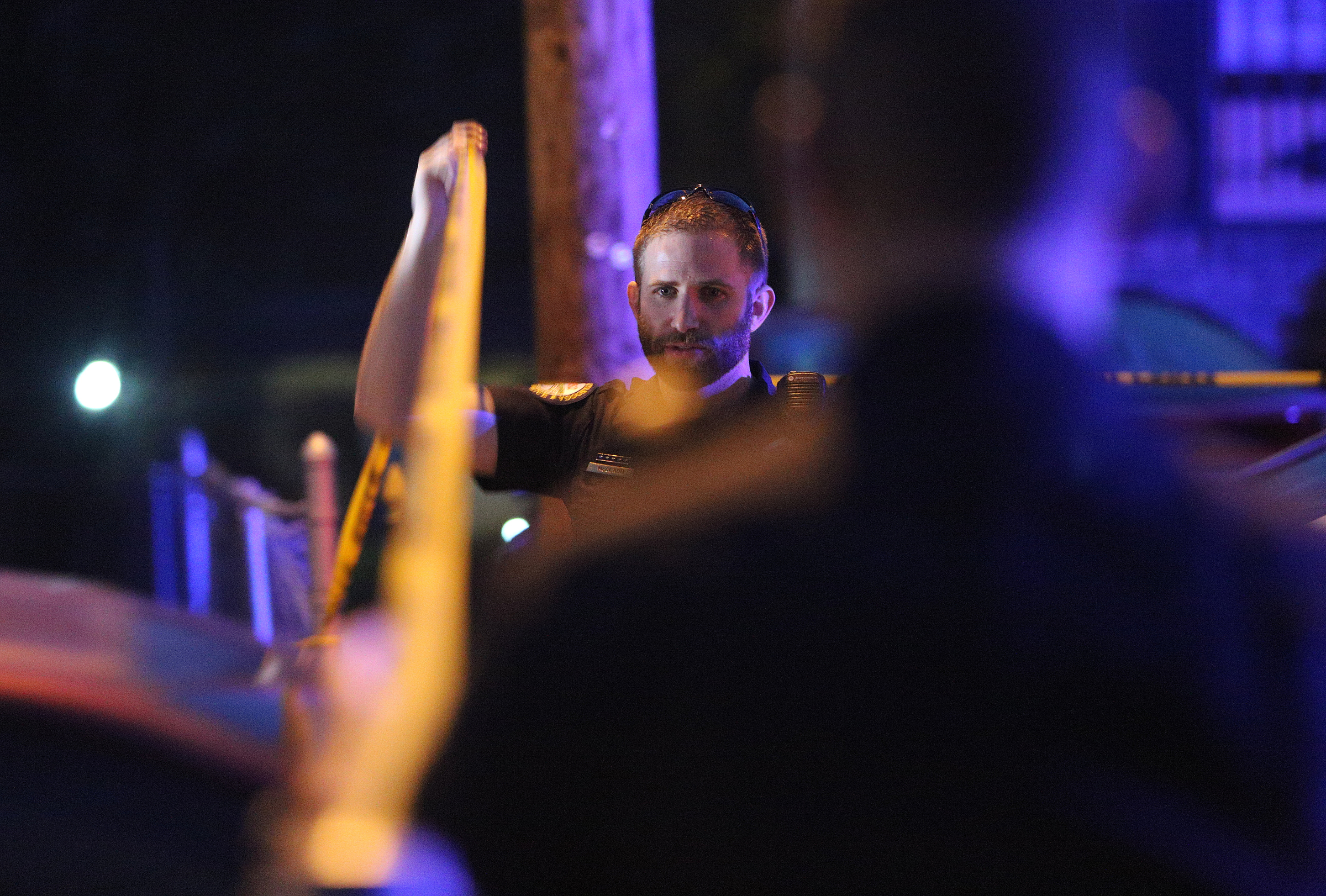 A Chattanooga police officer raises crime scene tape for a car exiting the scene of a shooting Tuesday, Feb. 20, 2018 in the 1400 block of Carousel Road in Chattanooga, Tenn. One person is deceased following the incident and another is in critical condition.