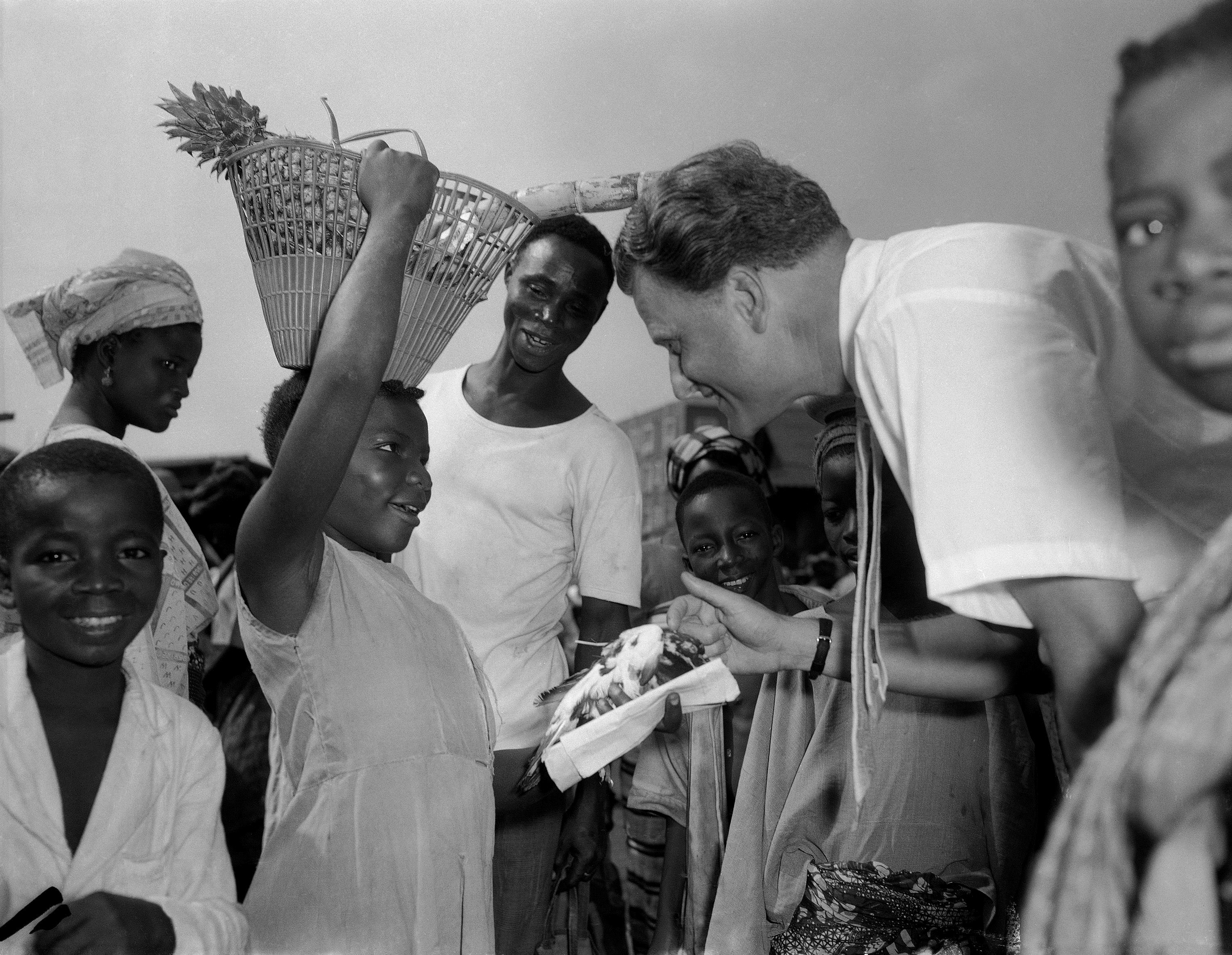 A little Nigerian girl, with a basket of fruit on her head, asks American evangelist Billy Graham to bless a pigeon she is holding in the market of Lagos, Nigeria, Jan. 28, 1960. Baptist preacher had just arrived in Nigeria from Ghana as part of his African mission tour. (AP Photo)