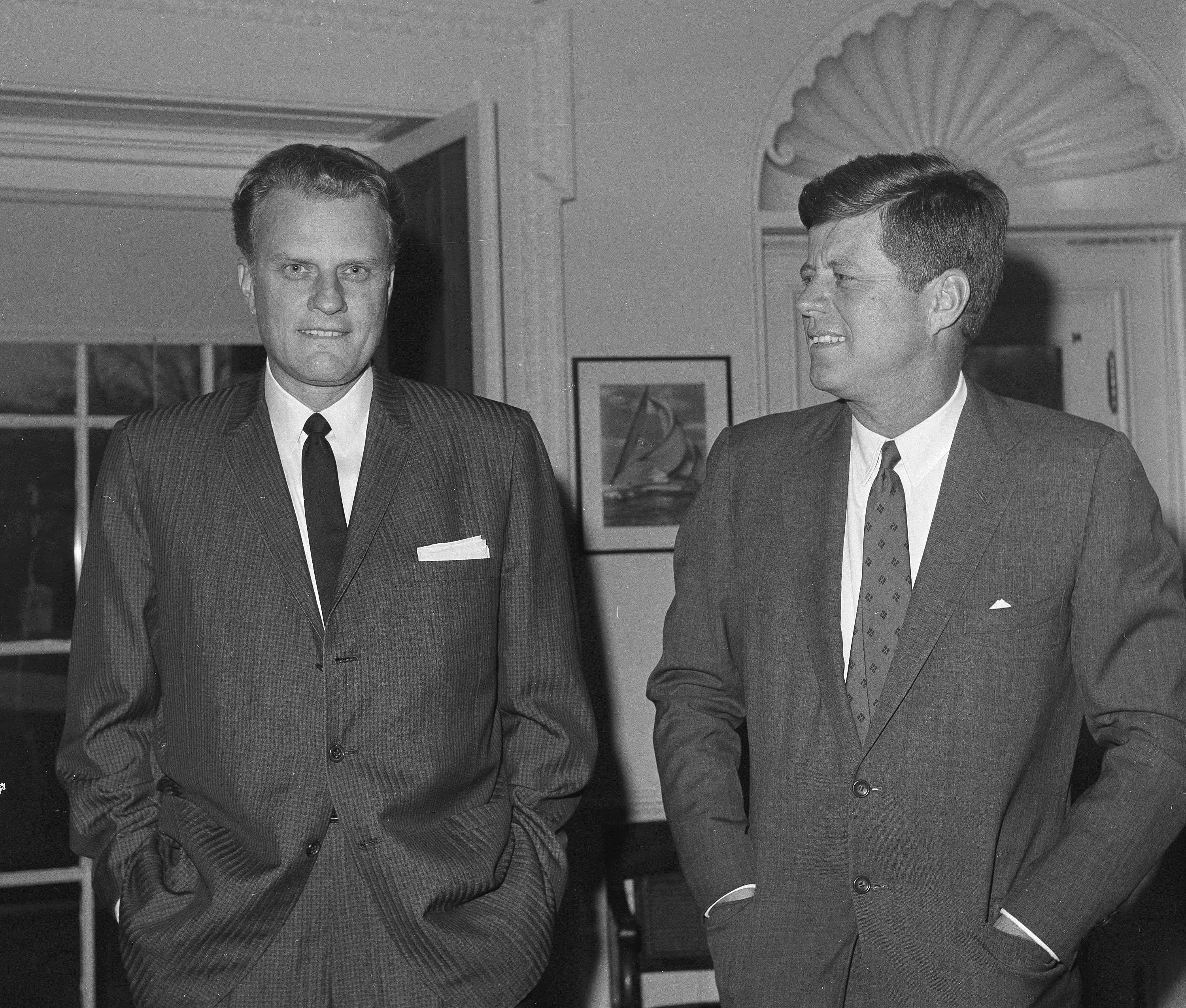 FILE - In this Dec. 12, 1961 file photo, Evangelist Billy Graham, left, talks with President John F. Kennedy during a call at the the White House in Washington. Graham, who transformed American religious life through his preaching and activism, becoming a counselor to presidents and the most widely heard Christian evangelist in history, has died. Spokesman Mark DeMoss says Graham, who long suffered from cancer, pneumonia and other ailments, died at his home in North Carolina on Wednesday, Feb. 21, 2018. He was 99. (AP Photo, File)