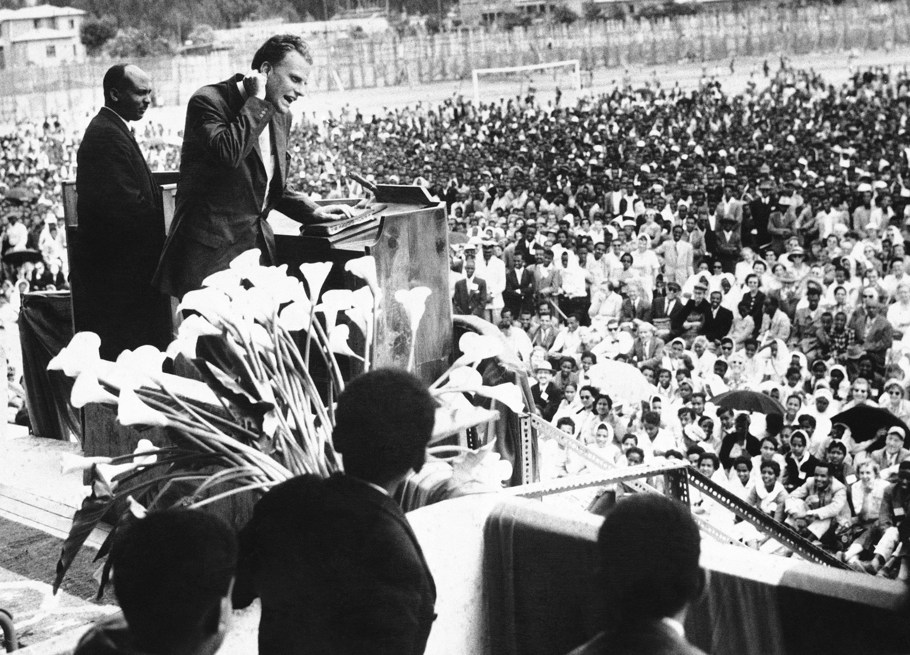 Billy Graham preaches to large crowd in football stadium at Addis Ababa, Ethiopia, March 15, 1960. The American evangelist, who is on a tour of Africa, met Jordan's King Hussein, Muslim protector of Christendom's most sacred shrines in Amman. The Jordanian monarch officially is guardian of the holy places in the Jerusalem and Bethlehem areas. (AP Photo)