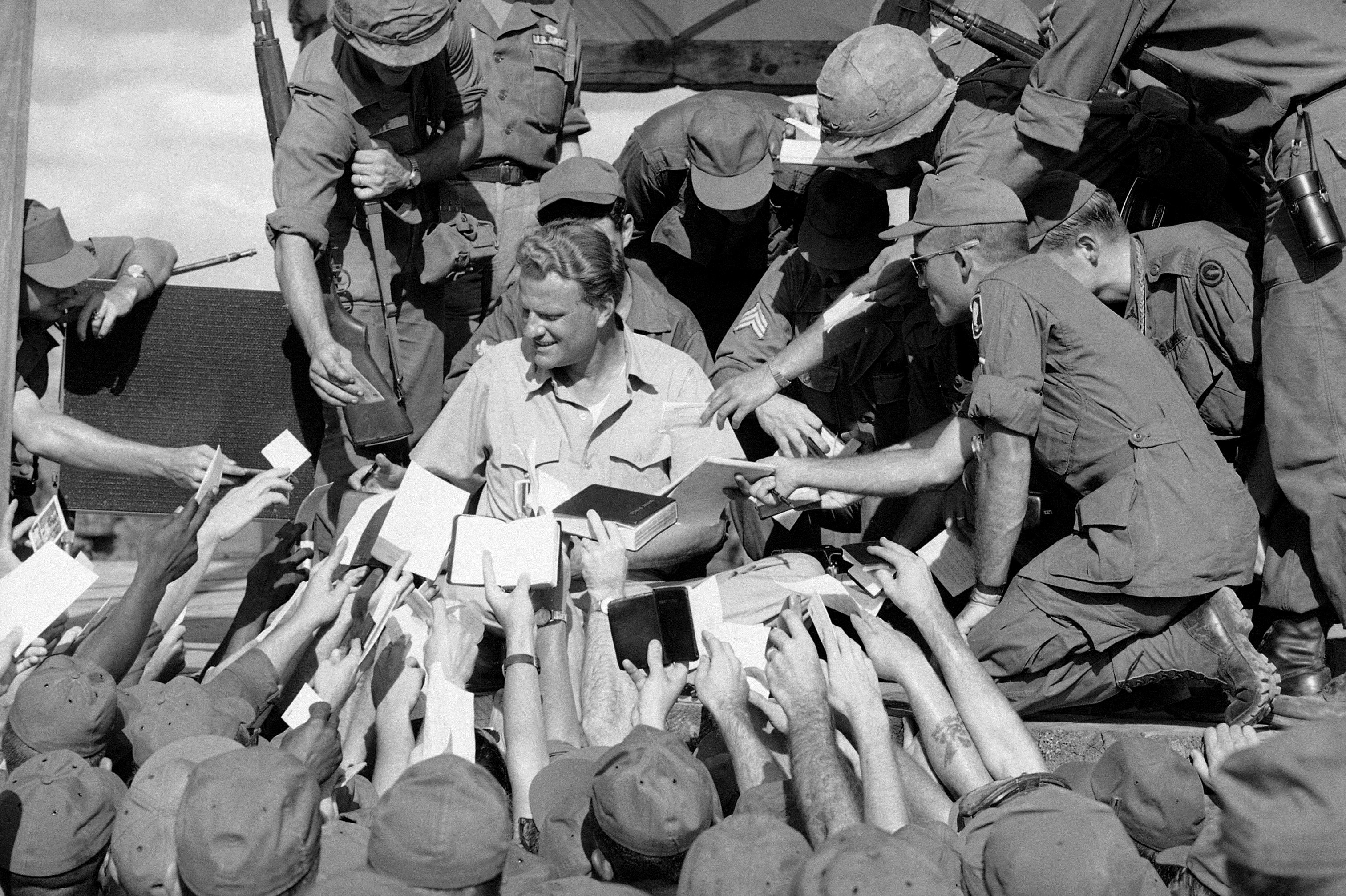 Scores of American GIs reach up to shake the hand and get his autograph after evangelist Billy Graham spoke to some 5,000 combat soldiers at the long Binh headquarters of field force II north of Saigon in South Vietnam, Dec. 22, 1966. (AP Photo)