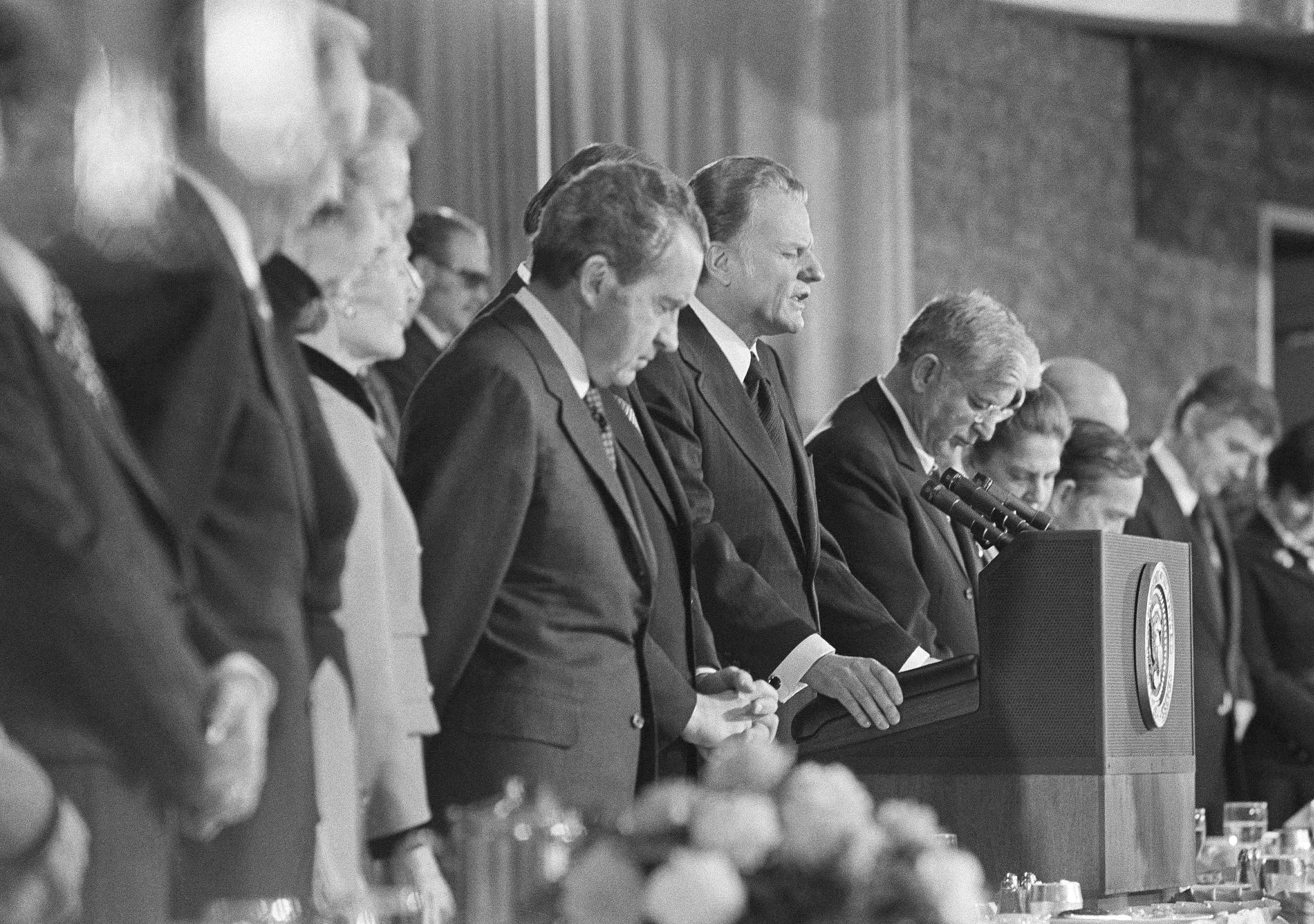 Rev. Billy Graham, center, gives the closing prayer at the National Prayer Breakfast at the Washington Hilton Hotel on Thursday, Feb. 1, 1973. U.S. President Richard Nixon, left, was among notables attending. Rep. Albert H. Quie, R-Minn., center, presided at the breakfast, a chore that Sen. John C. Stennis, D-Miss., was scheduled to handle. Stennis is in Walter Reed Medical Center recovering from gunshot wounds suffered in a Tuesday night holdup. (AP Photo)