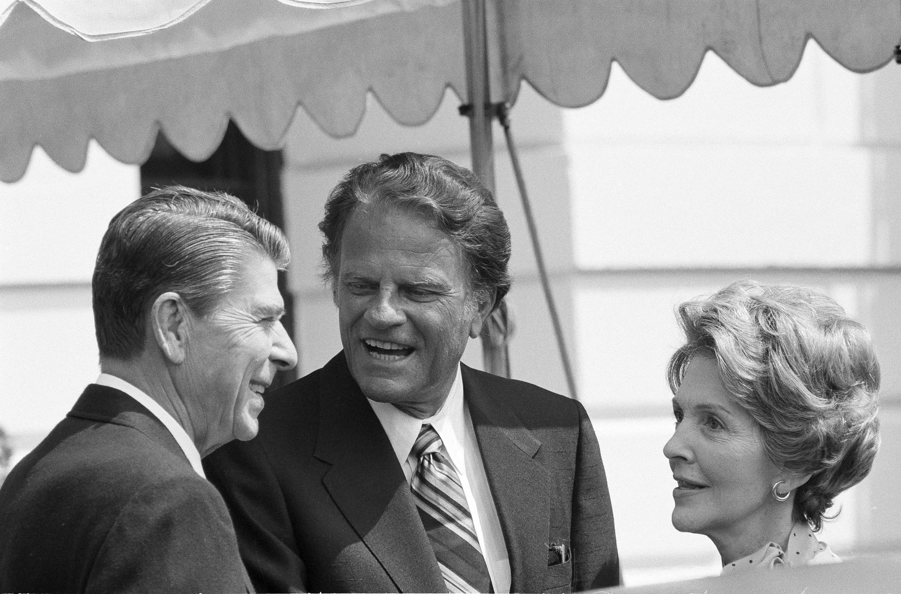The Rev. Billy Graham, center, chats with President Ronald Reagan and first lady Nancy Reagan at the White House, July 18, 1981, during a social call. (AP Photo/J. Scott Applewhite)