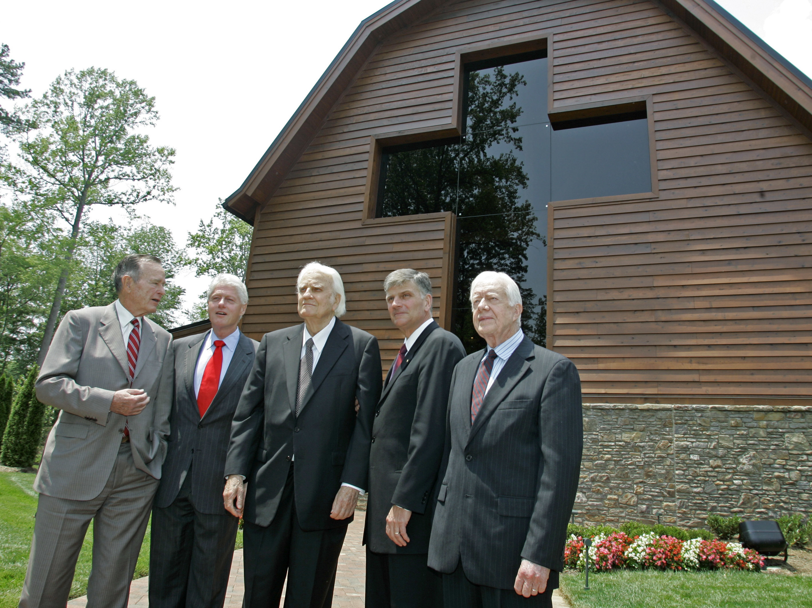 FILE - In this May 31, 2007 file photo, former Presidents, George H.W. Bush, left, Bill Clinton, second left, and Jimmy Carter, right, join Franklin Graham, second right, as they pose with Billy Graham, center, in front of the Billy Graham Library in Charlotte, N.C. Graham, who transformed American religious life through his preaching and activism, becoming a counselor to presidents and the most widely heard Christian evangelist in history, has died. Spokesman Mark DeMoss says Graham, who long suffered from cancer, pneumonia and other ailments, died at his home in North Carolina on Wednesday, Feb. 21, 2018. He was 99. (AP Photo/Chuck Burton, File)