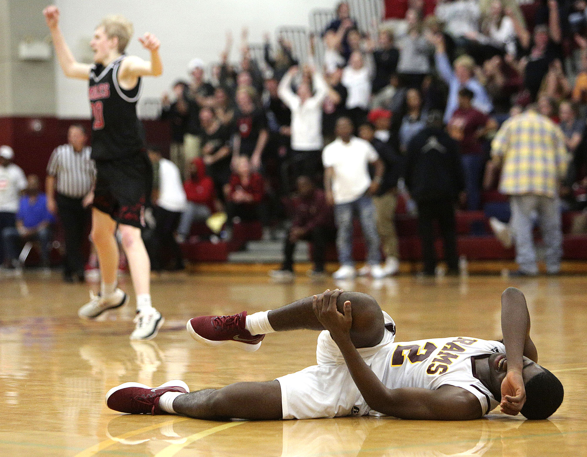 Tyner's Javon Craddock (2) fall son the ground injured as Signal Mountain celebrates scoring in the background during the District 6-AA boys' basketball championship game between Tyner and Signal Mountain Tuesday, Feb. 20, 2018 at Howard High School in Chattanooga, Tenn.
