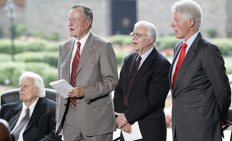 Billy Graham, left, listens as former Presidents George H.W. Bush, second from left, Jimmy Carter and Bill Clinton sing during a dedication ceremony for the Billy Graham Library in Charlotte, N.C., in 2007.