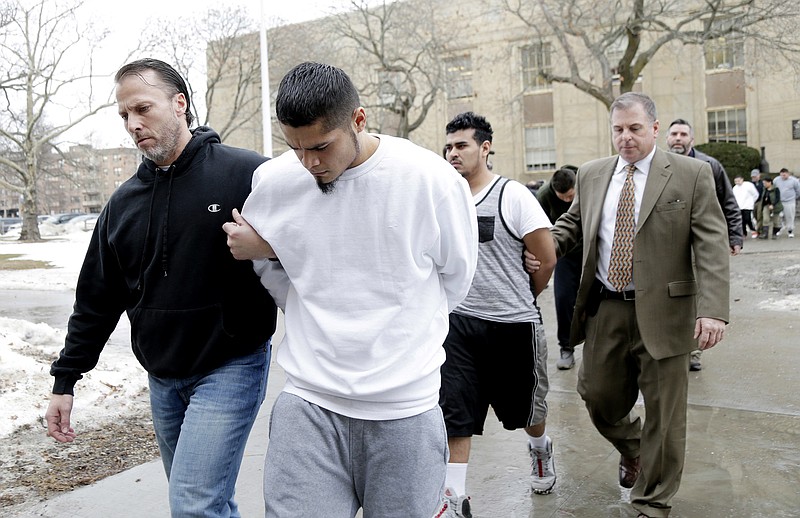 In this Jan. 11, 2018 file photo, suspected members of the MS-13 gang are escorted to their arraignment in Mineola, N.Y. A sweep of alleged MS-13 gang members on Long Island has racked up impressive arrest totals but also left unanswered questions. Since May, federal authorities say they've arrested more than 220 members of the notorious street gang. But authorities have largely declined multiple requests by for even the most basic information about the arrests. (AP Photo/Seth Wenig, File)