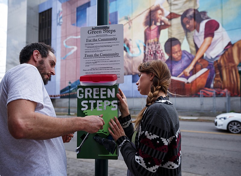 Green Steps director Alyssa Grizenko, right, and her husband Chris Sullivan install a Green Steps waste box at the corner of Martin Luther King Boulevard and Houston Street on Wednesday, Feb. 21, 2018, in Chattanooga, Tenn. Green Steps is one of several area nonprofits that have received donations from an anonymous bitcoin donor known as Pine.