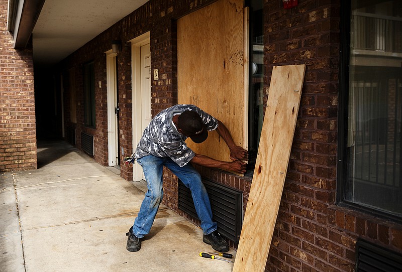 Geno Carter removes boards from the windows of a room at the Economy Inn on Brainerd Road on Thursday, Feb. 22, 2018, in Chattanooga, Tenn. Last week, residents of the inn were given one hour to collect their belongings and leave after the extended stay motel was closed as a nuisance by District Attorney Neal Pinkston.