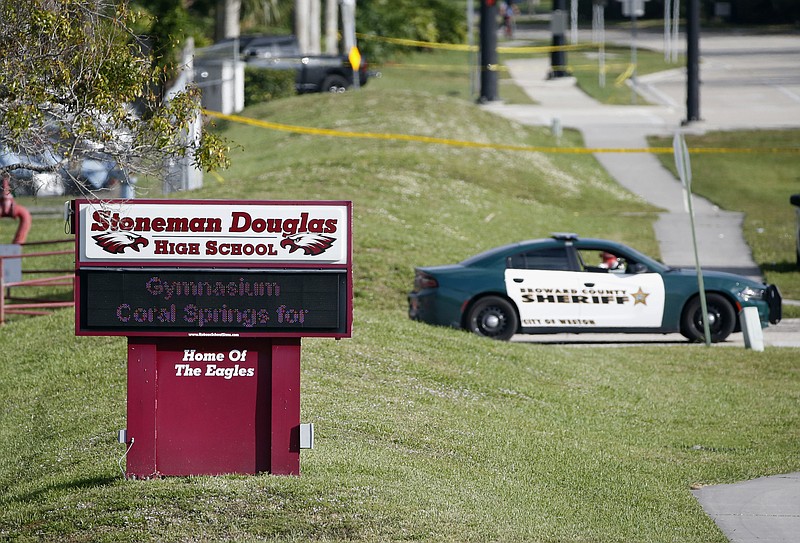 FILE- In this Feb. 15, 2018, file photo, Law enforcement officers block off the entrance to Marjory Stoneman Douglas High School, in Parkland, Fla., after a deadly shooting at the school. 
