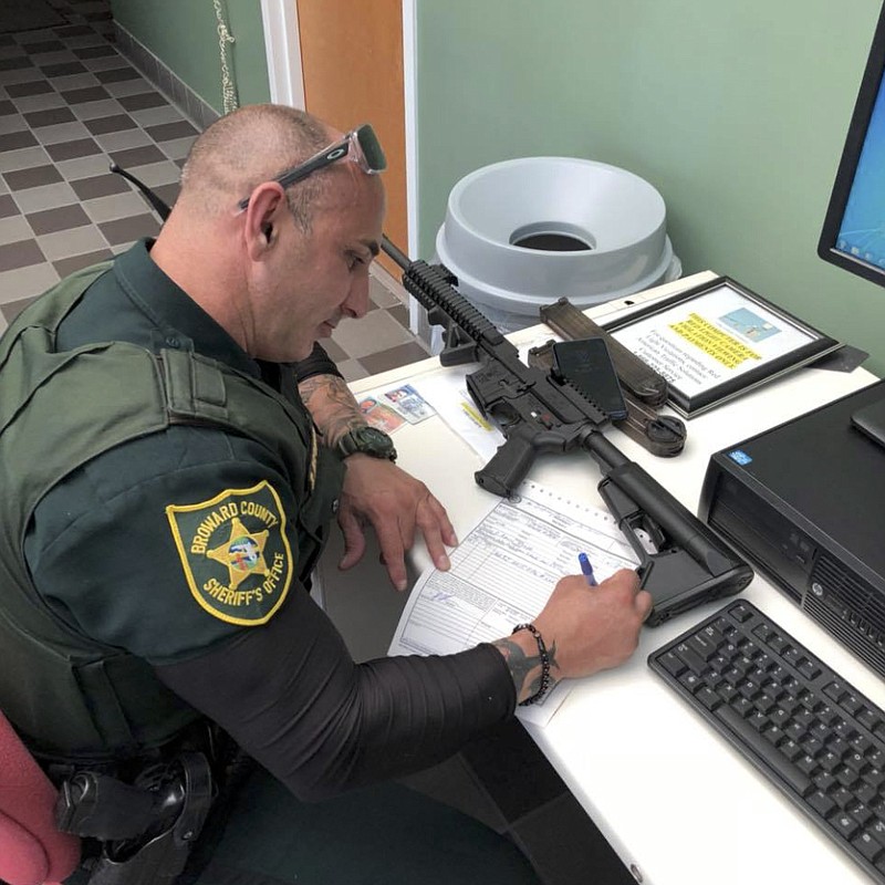 In this Feb. 16, 2018, photo provided by Ben Dickmann, a deputy at the Broward County sheriff's office in Ft. Lauderdale, Fla., processes paperwork to take possession of and destroy Dickmann's AR-style firearm. Dickmann decided to turn in his weapon after the shooting at Marjory Stoneman Douglas High School in nearby Parkland, Fla. (Ben Dickmann via AP)