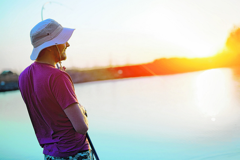 Fishing as recreation and sports displayed by fisherman at lake during sunset