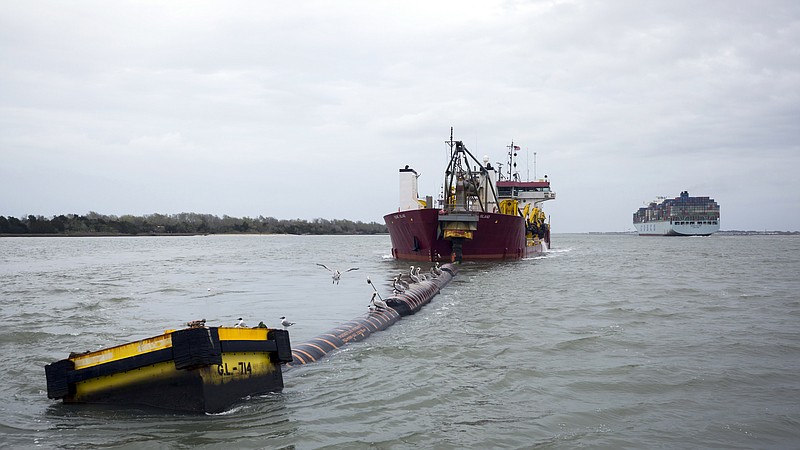 In this photo provided by the Georgia Port Authority, the container ship COSCO Glory, with a capacity of 13,100 twenty-foot equivalent container units, passes the dredge Padre Island as it works the Savannah Harbor entrance channel, on Tybee Island, Ga. The U.S. Army Corps of Engineers marked the completion of outer harbor dredging at the Port of Savannah Wednesday, as it reached the midpoint of the Savannah Harbor Expansion Project. (Stephen Morton/Georgia Port Authority via AP)