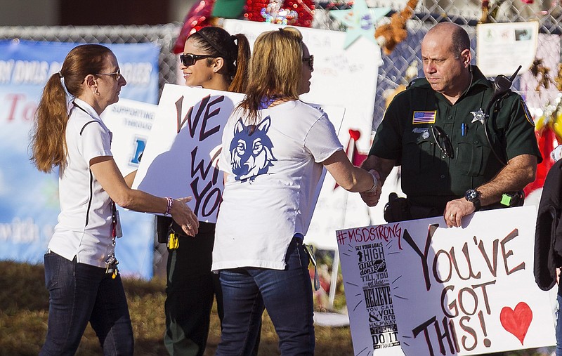 Faculty and staff greet police officers outside Marjory Stoneman Douglas High School in Parkland, Fla., last week as classes resumed for the first time since a Feb. 14 shooting.