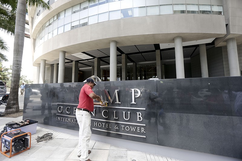 A man removes the word Trump, off a marquee outside the Trump Ocean Club International Hotel and Tower in Panama City, Monday, March 5, 2018. Escorted by police officers and a Panamanian judicial official, the owner of the Trump Panama City hotel has taken control of the property. A team of Trump security officials left the property. (AP Photo/Arnulfo Franco)
