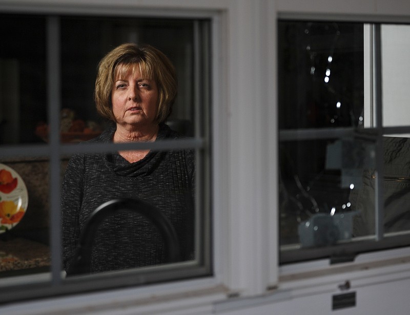Diana Parkinson poses for a portrait on Wednesday, March 7, 2018, in Rossville, Ga., seen from outside her home and framed by the broken window through which her husband, Mark, was shot and killed by a Walker County Sheriff's deputy on the night of Jan. 1. Mark walked into his kitchen with a handgun in response to his barking dogs when he was shot by an unseen deputy through the window, his wife says.