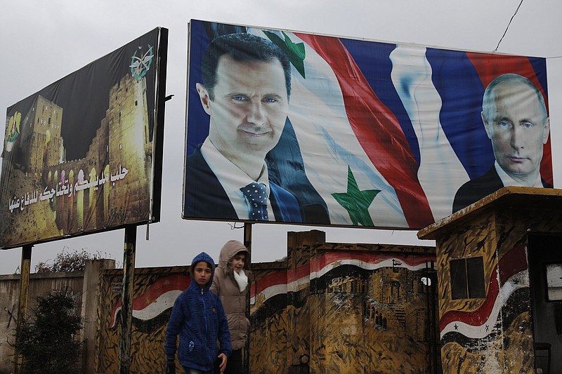 Syrian walk by posters of Syrian President Bashar Assad and Russian President Vladimir Putin in Aleppo, Syria, Thursday, Jan. 18, 2018. Syria said on Thursday its air defense would shoot down any Turkish jets that carry out attacks within Syria, a stark warning as tensions soar over apparent preparations by the Turkish military to invade a northern Syrian Kurdish enclave. Arabic on the left read, "Aleppo is your city and you need to defend it." (AP Photo/Hassan Ammar)