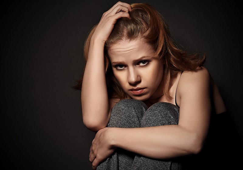 sad woman in depression and despair crying on black dark background