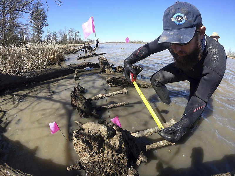 This Friday, March 2, 2018, photo shows Joseph Grinnan of SEARCH Inc. measuring an exposed shipwreck on a river bank near Mobile, Ala. Originally suspected to be the remains of the last ship to bring slaves to the United States, the wreck was determined to be something other than that vessel, the Clotilda. (Lee Anne Wofford/Alabama Historical Commission via AP)