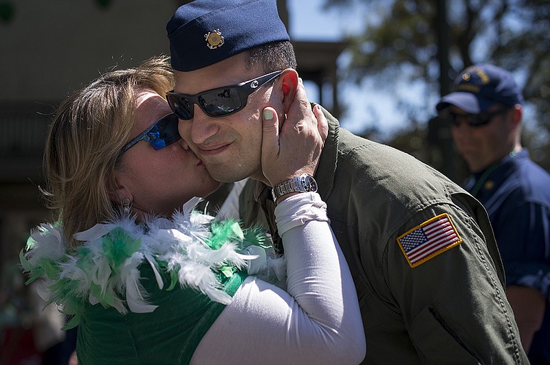 FILE - In a Friday, March 17, 2017 file photo, a woman kisses a member of the U.S. Coast Guard during Saint Patrick's Day Parade in Savannah, Ga. The Army wants to halt the favorite St. Patrick's Day shenanigan in Savannah that for decades has left marching soldiers with lipstick-smeared cheeks. Roughly 200 soldiers from nearby Fort Stewart are expected to march in the coastal Georgia city's sprawling St. Patrick's Day parade March 17, 2018. Traditionally, women wearing bright lipstick dart from the crowd to plant kisses on the faces of passing troops. A Fort Stewart spokesman and the parade's chief organizer said Thursday the Army wants the soldier smooching stopped. (Josh Galemore/Savannah Morning News via AP, File)