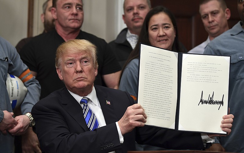 President Donald Trump holds up a proclamation on aluminum during an event in the Roosevelt Room of the White House in Washington, Thursday, March 8, 2018. He also signed one for steel. (AP Photo/Susan Walsh)