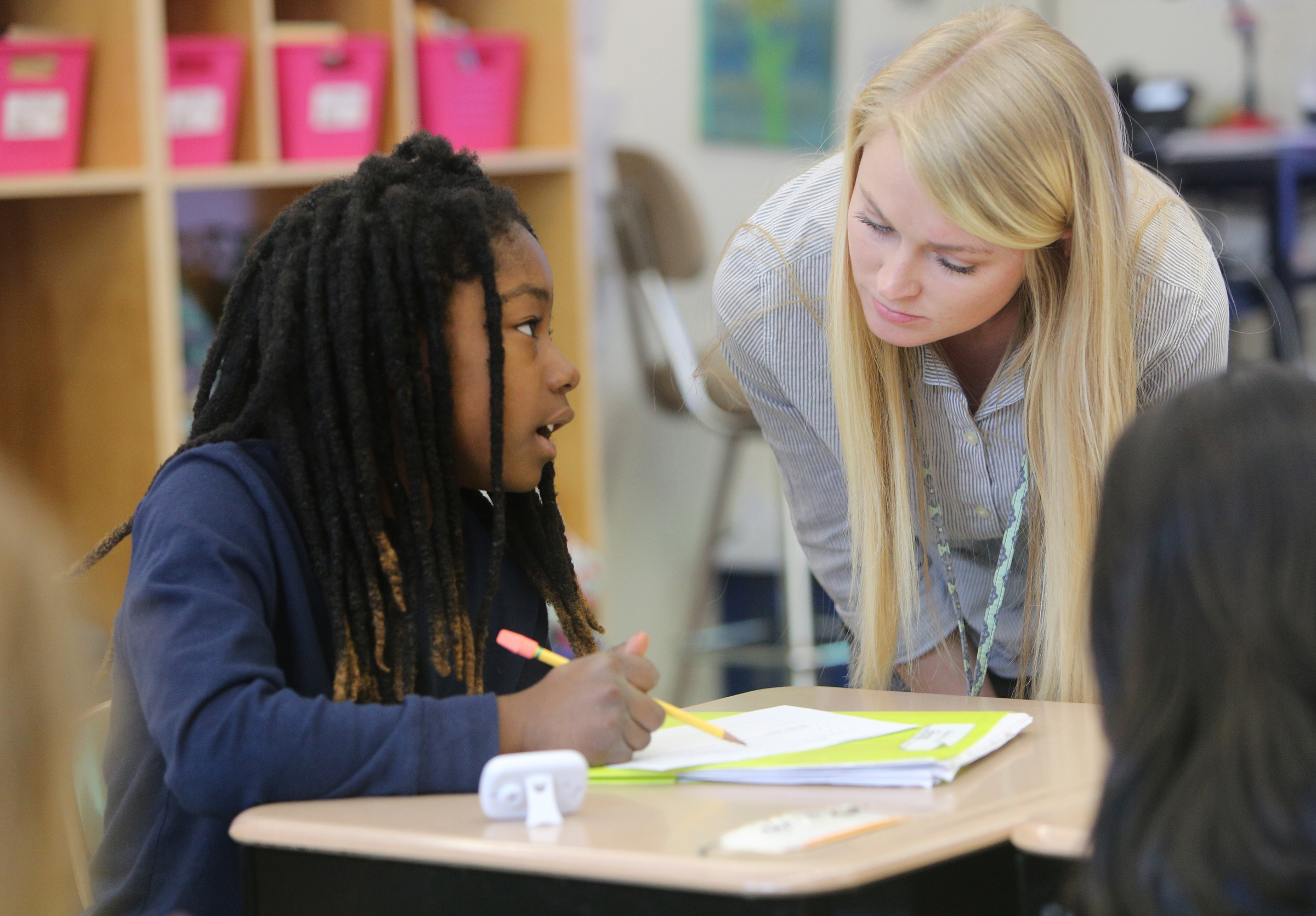 Artago Redding, 9, gets help from Christin Willingham, a student teacher from the University of Tennessee at Chattanooga, in Wendy Scruggs' class at Battle Academy Wednesday, March 7, 2018 in Chattanooga, Tenn. UTC is changing how it prepares students to be teachers by expanding the length of time students spend as student teachers during their residency semesters.