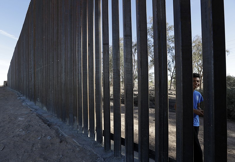 In this March 5, 2018, photo, a boy looks through the first section of a newly-constructed structure along the border separating Mexicali, Mexico, right, and Calexico, Calif. As Donald Trump prepares for his first visit to the U.S.-Mexico border as president, little has changed despite the heated rhetoric. (AP Photo/Gregory Bull)